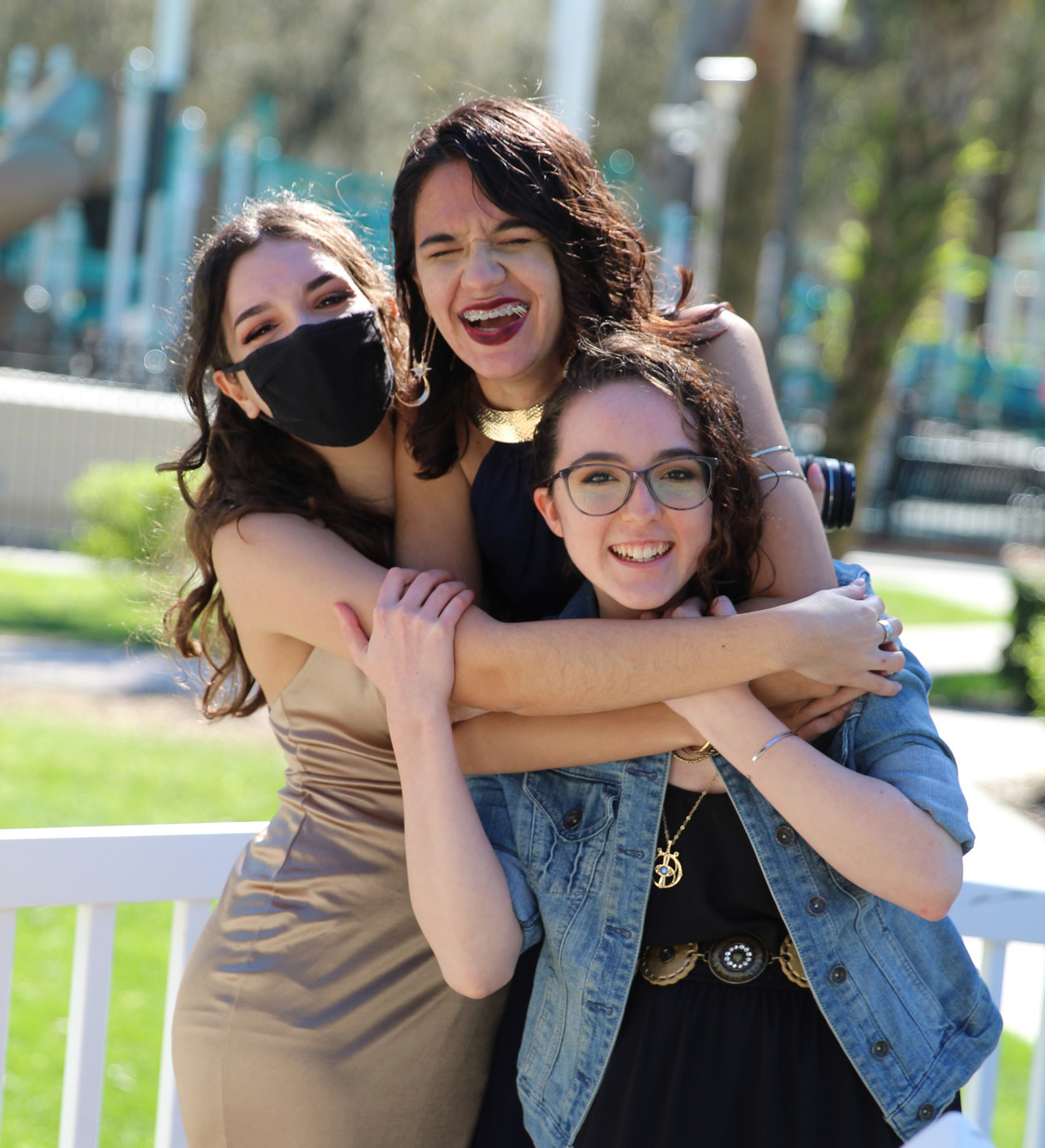 Three students outside hugging each other and smiling