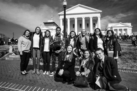 A group of about 11 students posing for a photo at the steps of the Virginia General Assembly. 