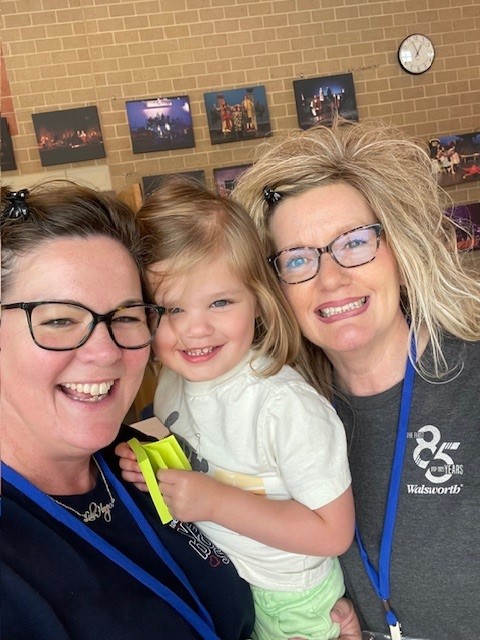 Two customer service representatives with an elementary school kid standing and posing for a photo. 